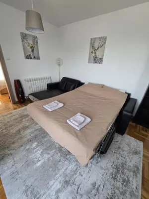 a bed in a living room with two towels on it at Apartman Emi in Belgrade
