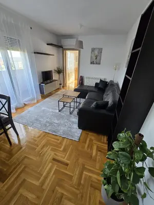 a living room with a black couch and wooden floors at Apartman Emi in Belgrade