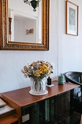 a vase of flowers sitting on a table under a mirror at Sweet House Retro in Belgrade