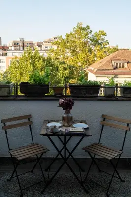 a table with two chairs and a vase of flowers on a balcony at Sweet House Retro in Belgrade