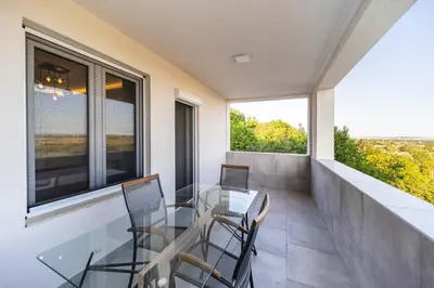 a glass table and chairs on a balcony with windows at Anja D Apartments in Belgrade