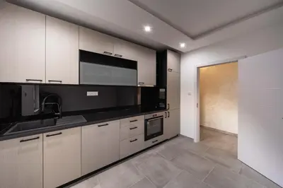 a kitchen with white cabinets and black appliances at Anja D Apartments in Belgrade