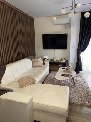 a living room with a white couch and a tv at Freedom APARTMAN RUMA in Ruma