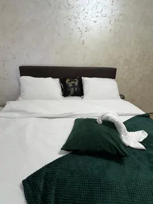 a bed with a green blanket and a white duck on it at Freedom APARTMAN RUMA in Ruma