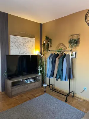 a living room with a tv and a rack of clothes at Mikos apartmani in Belgrade
