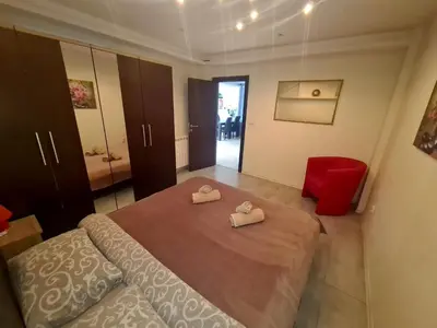 a bedroom with a large bed and a red chair at Fantastic Belgrade Nights II in Belgrade