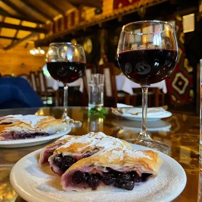 a table with two plates of food and two glasses of wine at Vila Aleksandar in Orašac