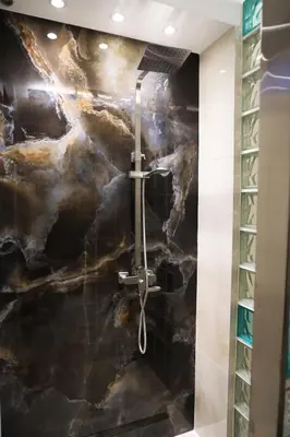 a bathroom with a marble wall with a shower at Point Apartman in Belgrade
