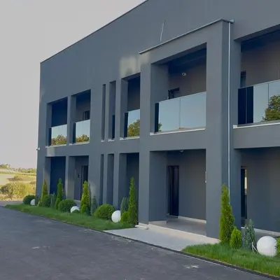 a gray building with bushes in front of it at Apartmani Tanasijević