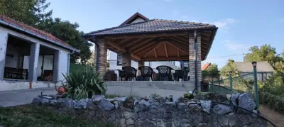a wooden gazebo with chairs and a stone wall at Vila Terasa in Čortanovci