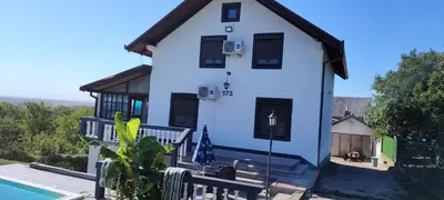 a white house with black windows and a pool at Vila Terasa in Čortanovci