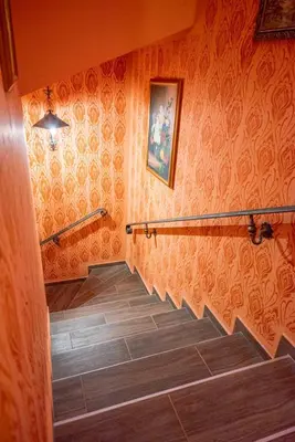 a staircase in a room with orange wallpaper at Etno kuća Biblioteka in Smederevo