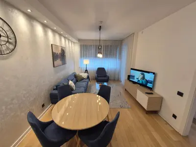 a living room with a table and a couch and a tv at A Blok Modern Apartment in Belgrade