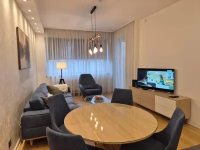a living room with a table and a tv at A Blok Modern Apartment in Belgrade