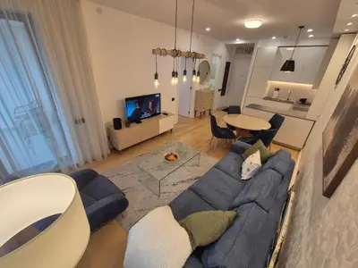 a living room with a blue couch and a table at A Blok Modern Apartment in Belgrade