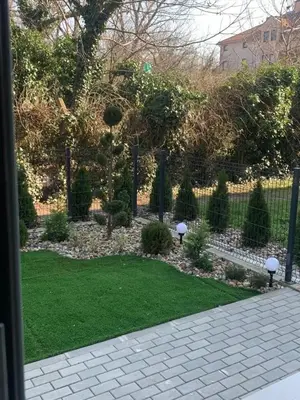 a garden with green grass and a fence at Apartman M&A in Inđija