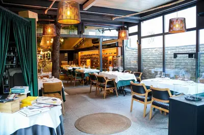a restaurant with white tables and chairs and windows at Boutique Hotel Aviator in Belgrade