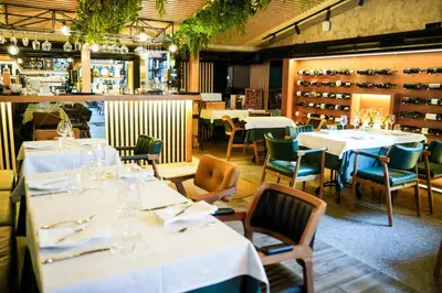 a restaurant with white tables and chairs and wine racks at Boutique Hotel Aviator in Belgrade
