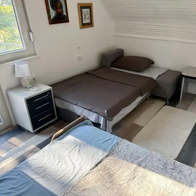 a room with three beds and a table and a window at Pokito House on the Hill in Sremski Karlovci