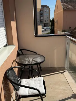 a balcony with two chairs and a table and a window at Petra in Stara Pazova