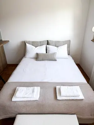 a large white bed with two white towels on it at Limpio Apartman 2 in Belgrade
