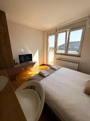 a bedroom with a large white bed and a tv at Limpio Apartman 2 in Belgrade