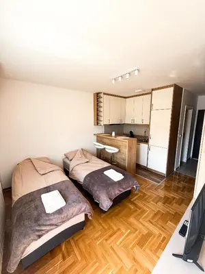 two beds in a room with a kitchen at Limpio Apartman 2 in Belgrade