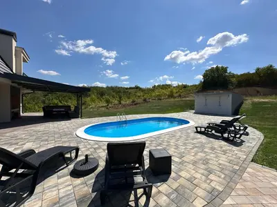 a patio with a pool with chairs and a table at Vila Remeta in Velika Remeta