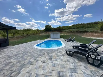 a swimming pool on a patio with two chairs and a table at Vila Remeta in Velika Remeta