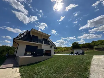 a white house with a blue sky with clouds at Vila Remeta in Velika Remeta