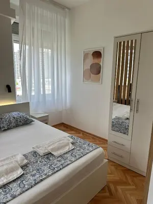 a white bedroom with a bed and a large window at URBAN Suites in Belgrade