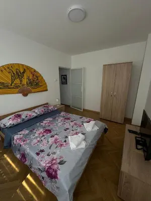 a bedroom with a large bed with a floral bedspread at MT Apartman in Belgrade