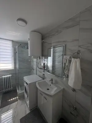 a bathroom with a sink and a washing machine at MT Apartman in Belgrade