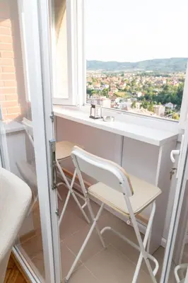 a chair sitting in front of a desk in a window at Apartman Horizont in Arandjelovac