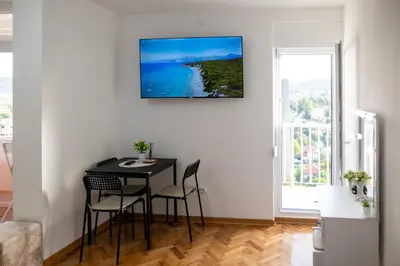 a dining room with a table and chairs and a window at Apartman Horizont in Arandjelovac