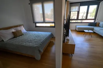 a bedroom with a bed and a living room with a couch at GueZt Dobanovačka 93A in Belgrade