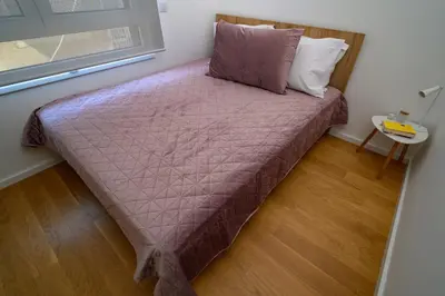a bed with a purple comforter in a room at GueZt Dobanovačka 93A in Belgrade