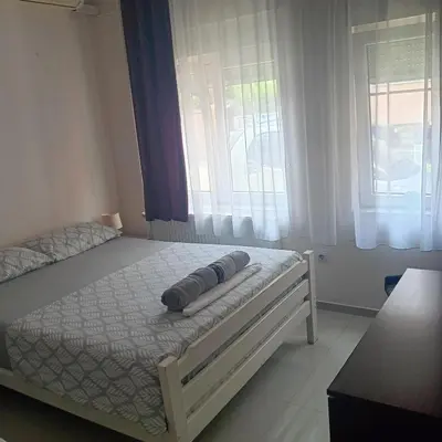 a bed in a bedroom with two windows at Vila Eni in Smederevo
