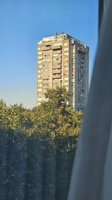 a tall building on top of a hill with a tree at Sunny Danube Quay Luxe Studio in Belgrade