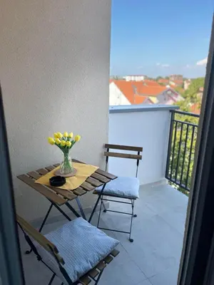 a table and chairs on a balcony with a vase of flowers at TaMiLux apartments in Belgrade