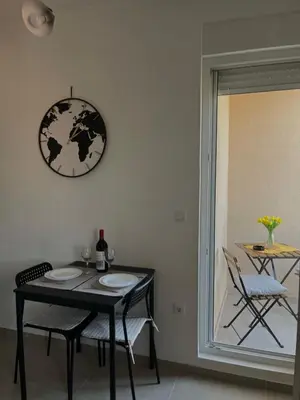 a dining room table with two chairs and a clock on the wall at TaMiLux apartments in Belgrade