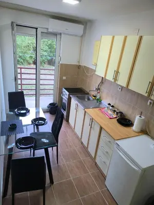 a small kitchen with a table and a table and chairs at R & P Apartman 2 Mladenovac in Mladenovac