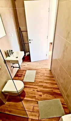a bathroom with a toilet and a sink on a wooden floor at Amar 2 in Belgrade
