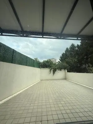 an empty parking lot with a wall and trees at Amar3 in Belgrade