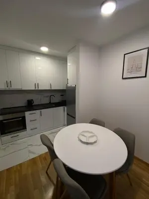 a white kitchen with a white table and chairs at Apartman P&N Stara Pazova in Stara Pazova