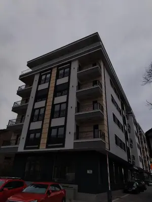 a tall building with cars parked in front of it at Apartman P&N Stara Pazova in Stara Pazova