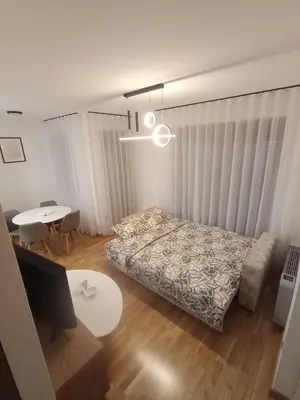 a bedroom with a bed and a table and a desk at Apartman P&N Stara Pazova in Stara Pazova