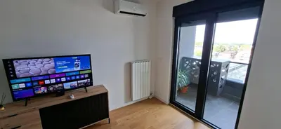 a living room with a flat screen tv and a window at Park Vila apartment in Belgrade