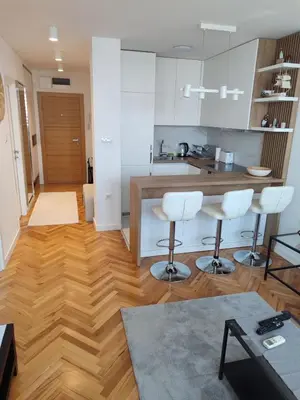 a kitchen with wooden floors and white cabinets and white stools at New Belgrade Cozy Base in Belgrade