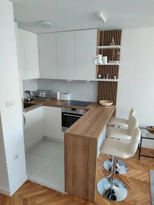 a kitchen with white cabinets and a counter and a stool at New Belgrade Cozy Base in Belgrade